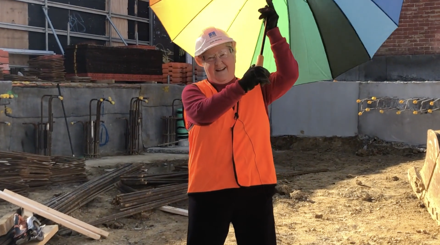 Jude on site holding Rainbow coloured umbrella