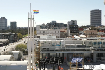 Drone footage of pride centre roof with flagpole flying the rainbow pride flag