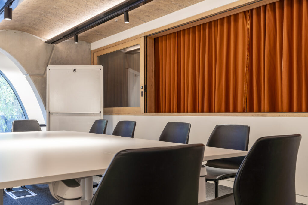 Mezzanine Room; medium shot of tables and chairs, whiteboard, window overlooking the Theatrette with orange velvet curtains