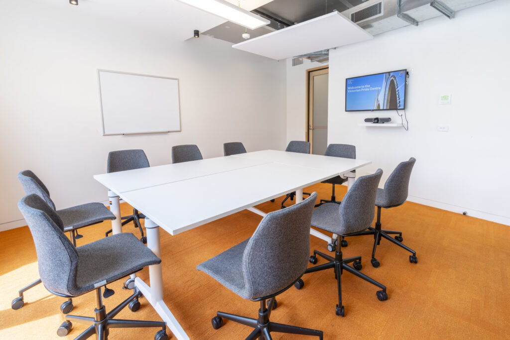 Meeting Room 4; Chairs and tables in the middle of the room with a TV behind. Carpeted room.