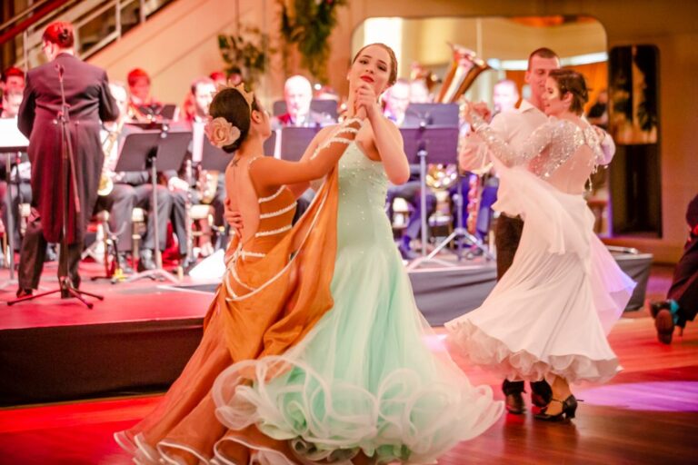 Two Ballroom dancers dance in front of an orchestra