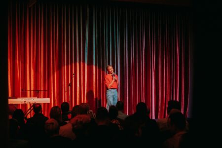 Comedian Aurelia St Claire on stage holding a microphone.