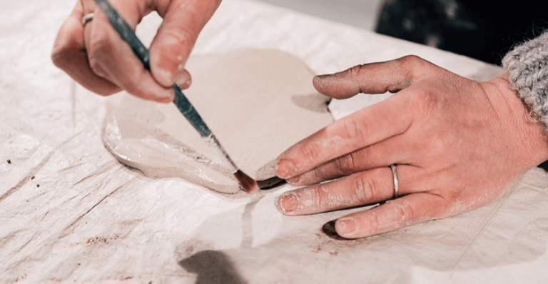 hands in the frame working with clay (pottery)