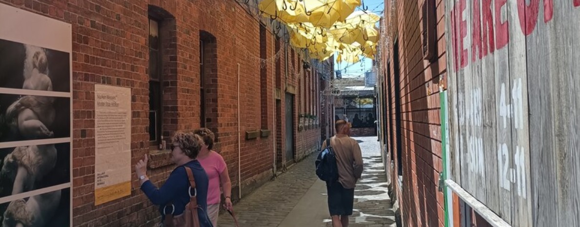 A laneway exhibition with three people walking through the alley