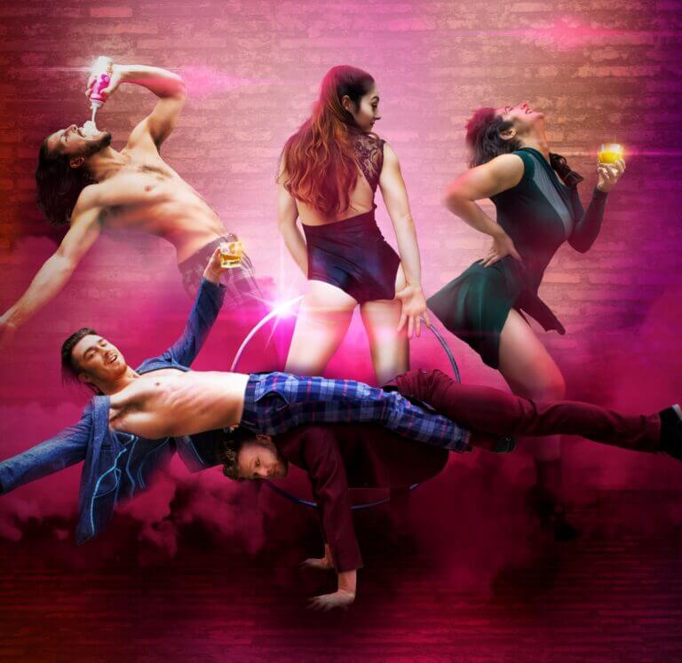 Five circus performers pose for the camera against a brick background with a smoky red overlay.