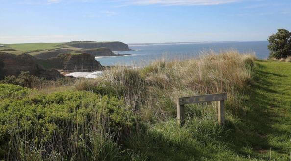 Cliffs and a large body of ocean. There is a sign that is unreadable in the foreground.