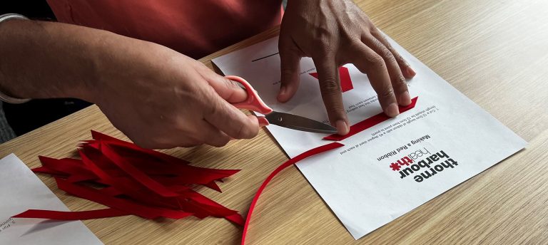 A close up of a person's hand cutting ribbons Infront of Thorne Harbour Health documents