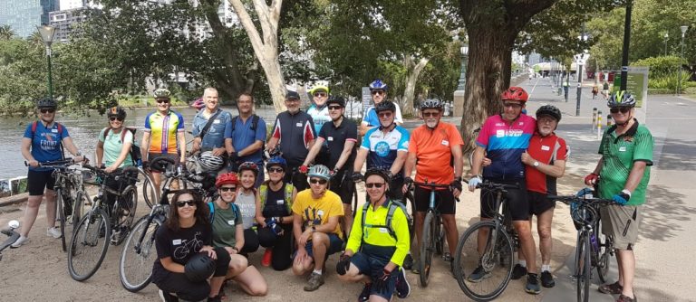 A large group of people with bikes smile at the camera