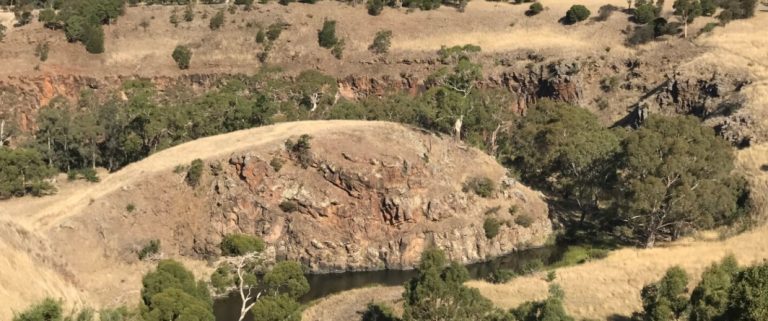 Deep Creek Chintin - an areal shot of the creek with rocks, trees and dry grass.