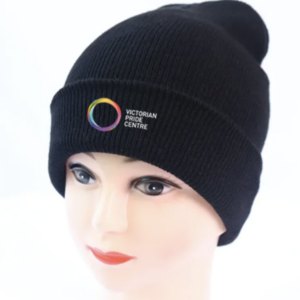 Victorian Pride Centre circle and title upon a black beanie. The beanie sits on top of a mannequin head.