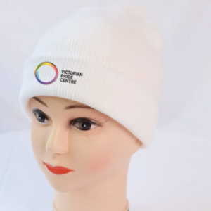 A white beanie with the Victorian Pride Centre circle and text displayed on a mannequin head