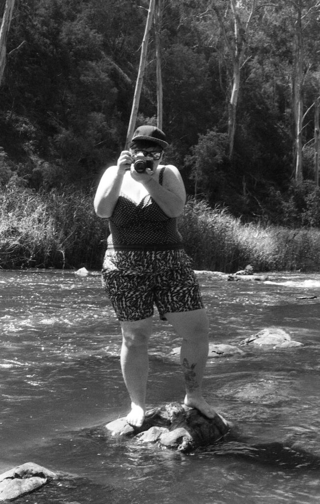 Person taking photograph with camera in river