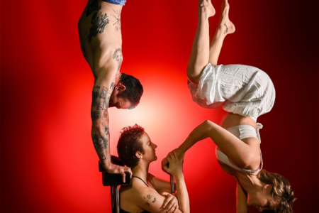 Circus performers performing handstands. There are three people that are connected.