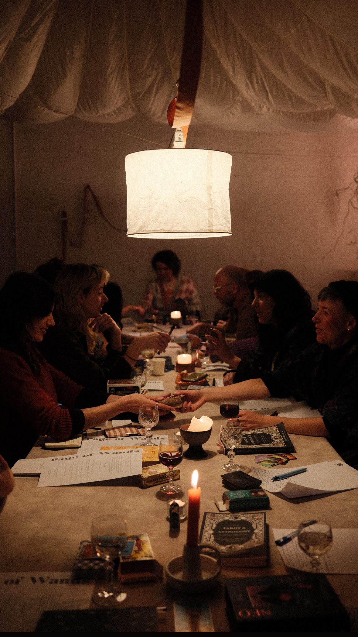 Tarot club, dim lighting, people gathering around a table