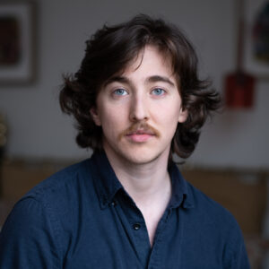 Oliver Ayres square headshot. He is looking directly at the camera in a collared shirt.